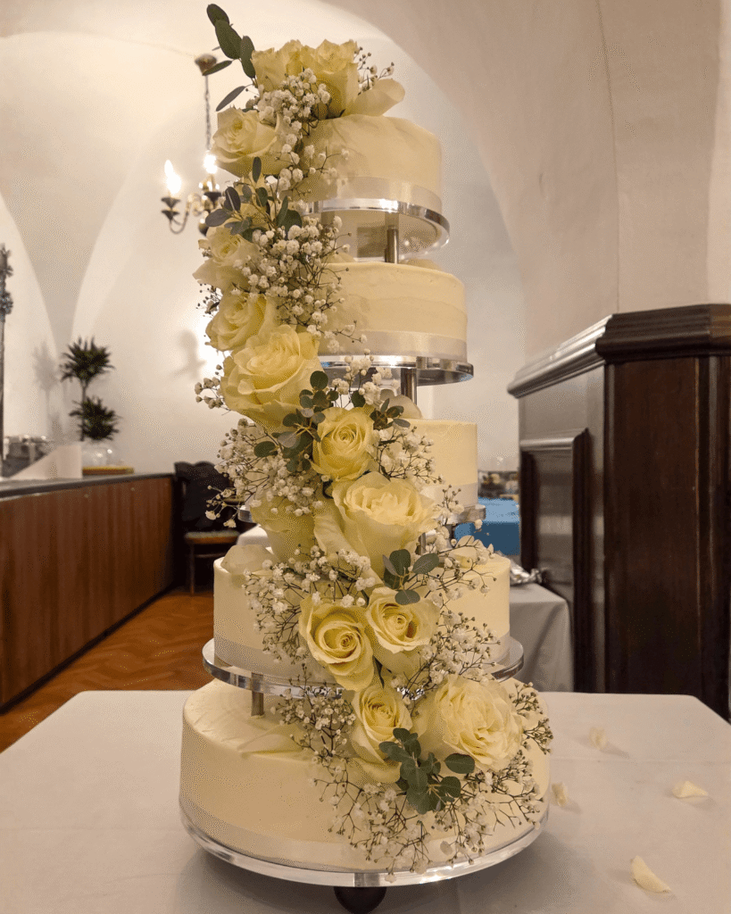 Moderna večnadstropna poročna torta Taca z asimetrično postavitvijo in rumenimi cvetličnimi detajli.